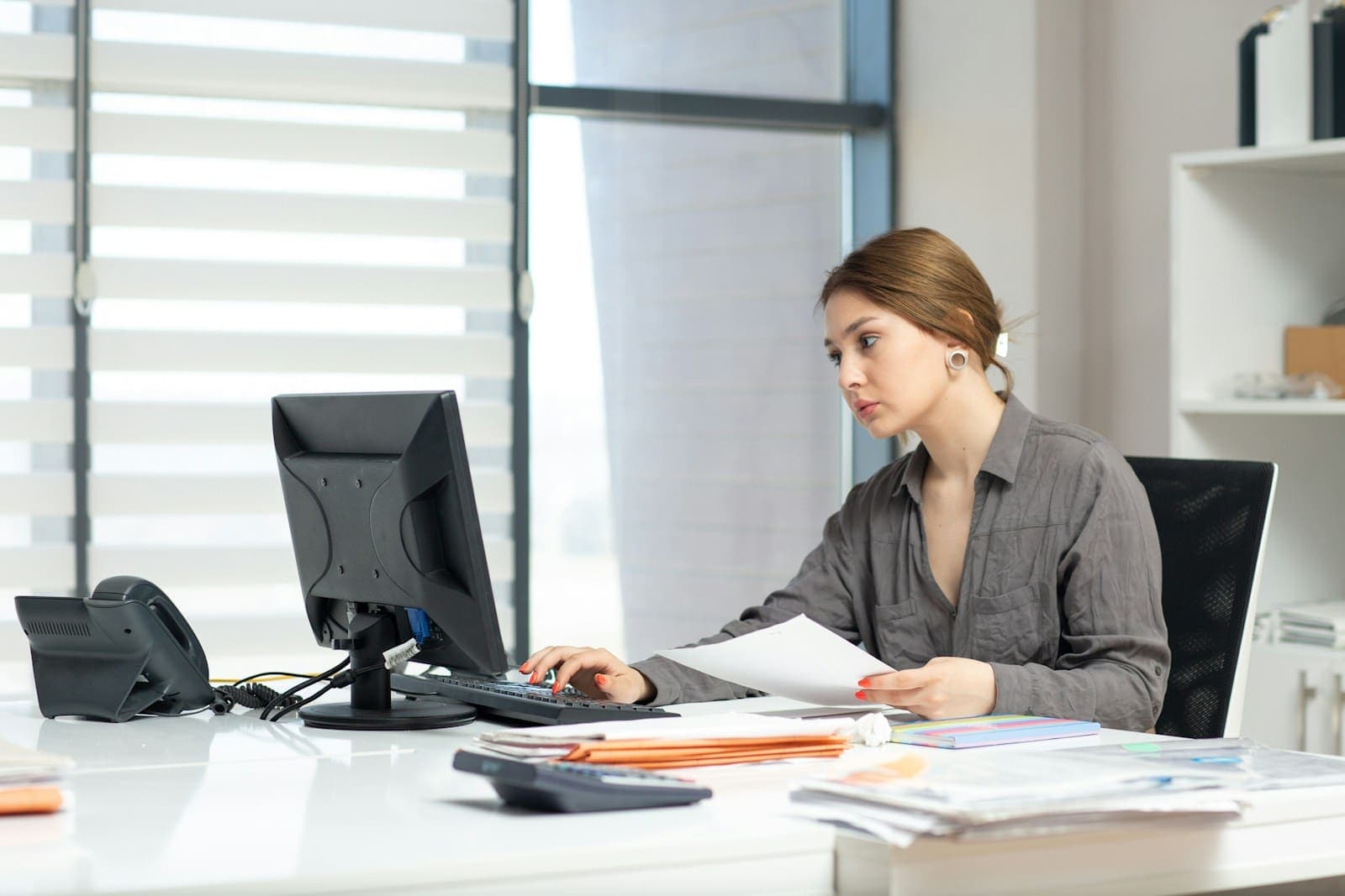 Profissional conferindo documentos financeiros no computador